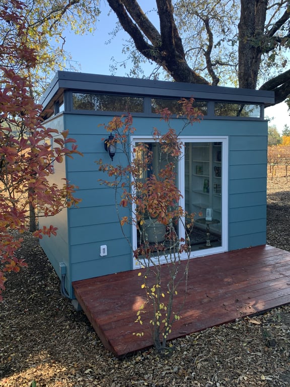 A blue-green shed in fall foliage.