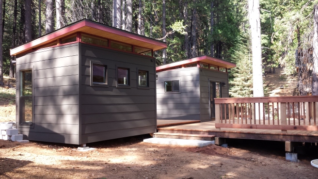 The two sheds are connected to a cabin via a custom deck. 